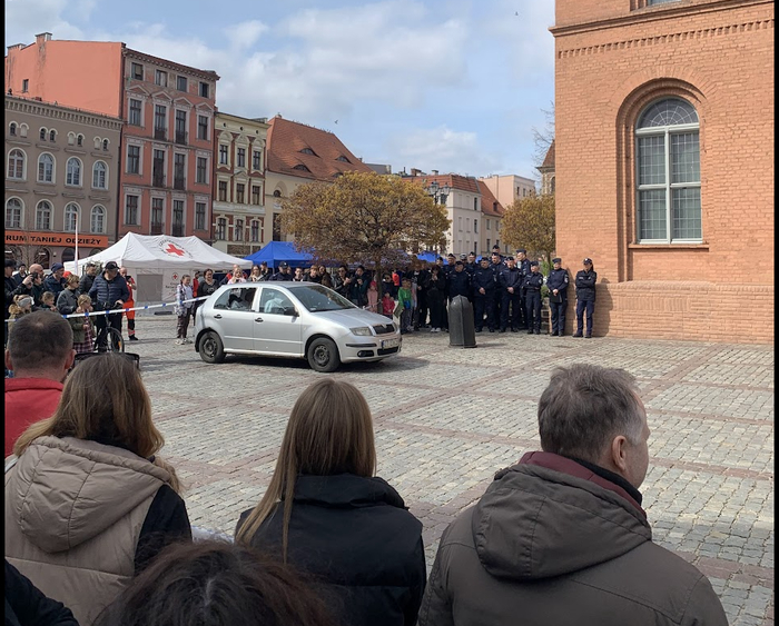 Преступники (на самом деле переодетые полицейские) разбили заднее окно и уселись в автомобиль - обыватели глазеют на шоу.