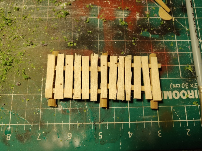 Пока гипс высыхал я сделал забор. Доски вырезал из деревянных шпателей, а в качестве бревен отлично подошли бамбуковые палочки. В конце забор застарил при помощи той же темно-серой смывки.