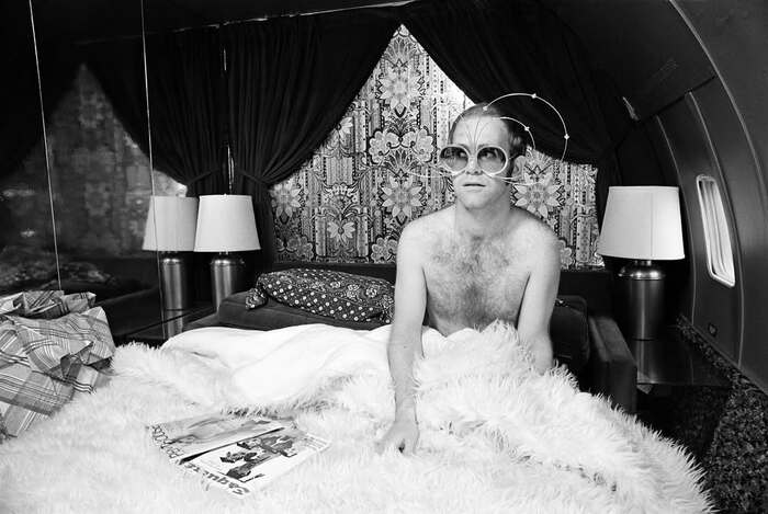 Элтон Джон в кровати на борту его личного самолета, 1975.