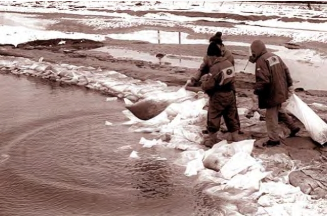 Рабочие пытаются перекрыть прорыв мешками с песком.